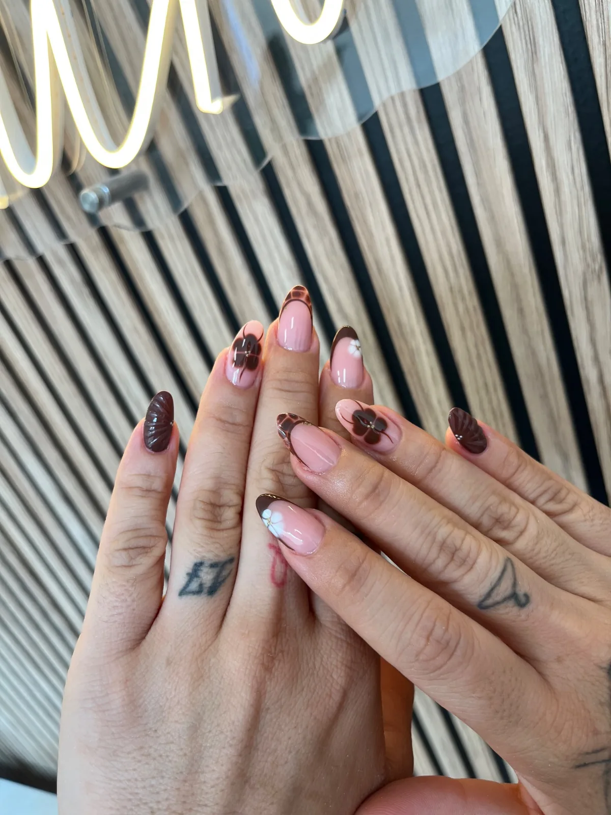 Manos con uñas rosa y marrón con francesa y diseños de nail art