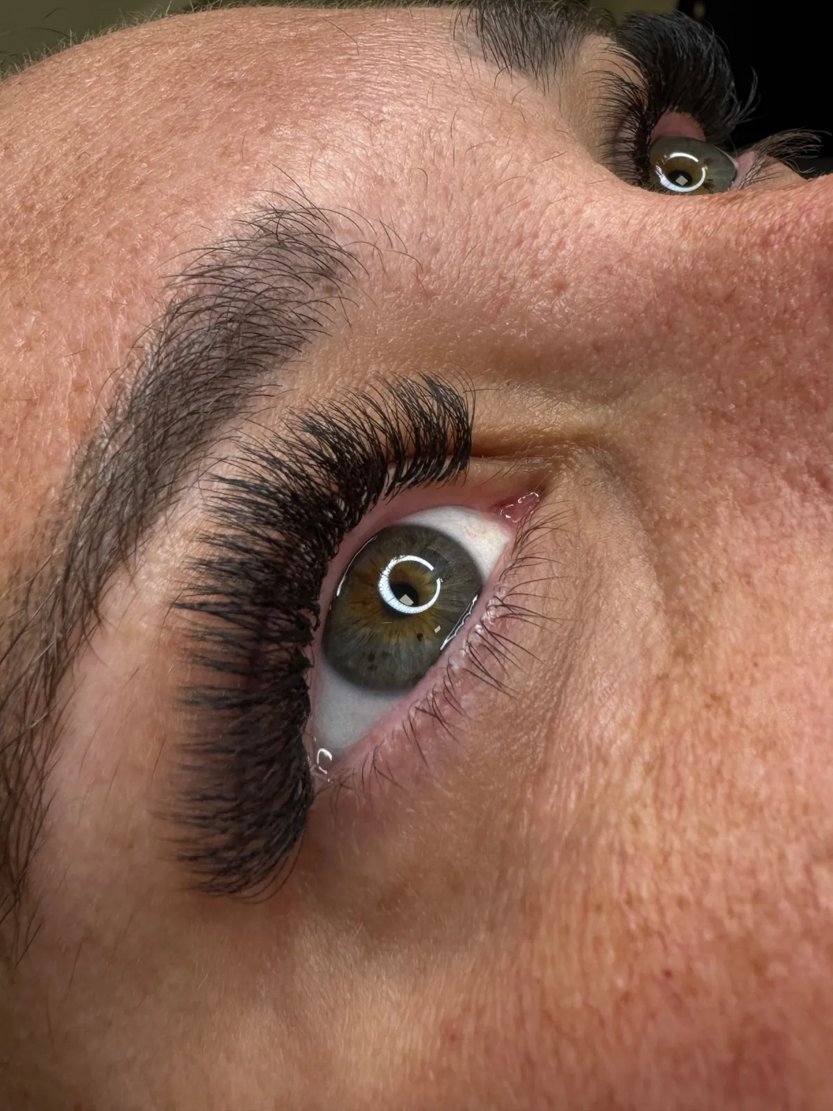 Ojo en primer plano con extensiones de pestañas de volumen y ceja perfilada
